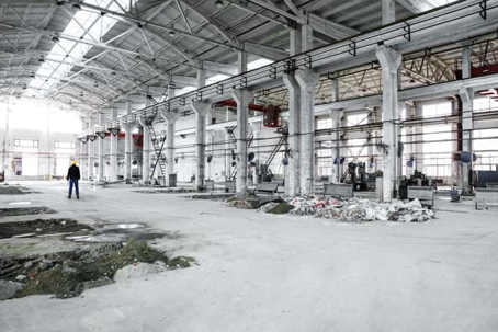 industrial worker in large, derelict factory